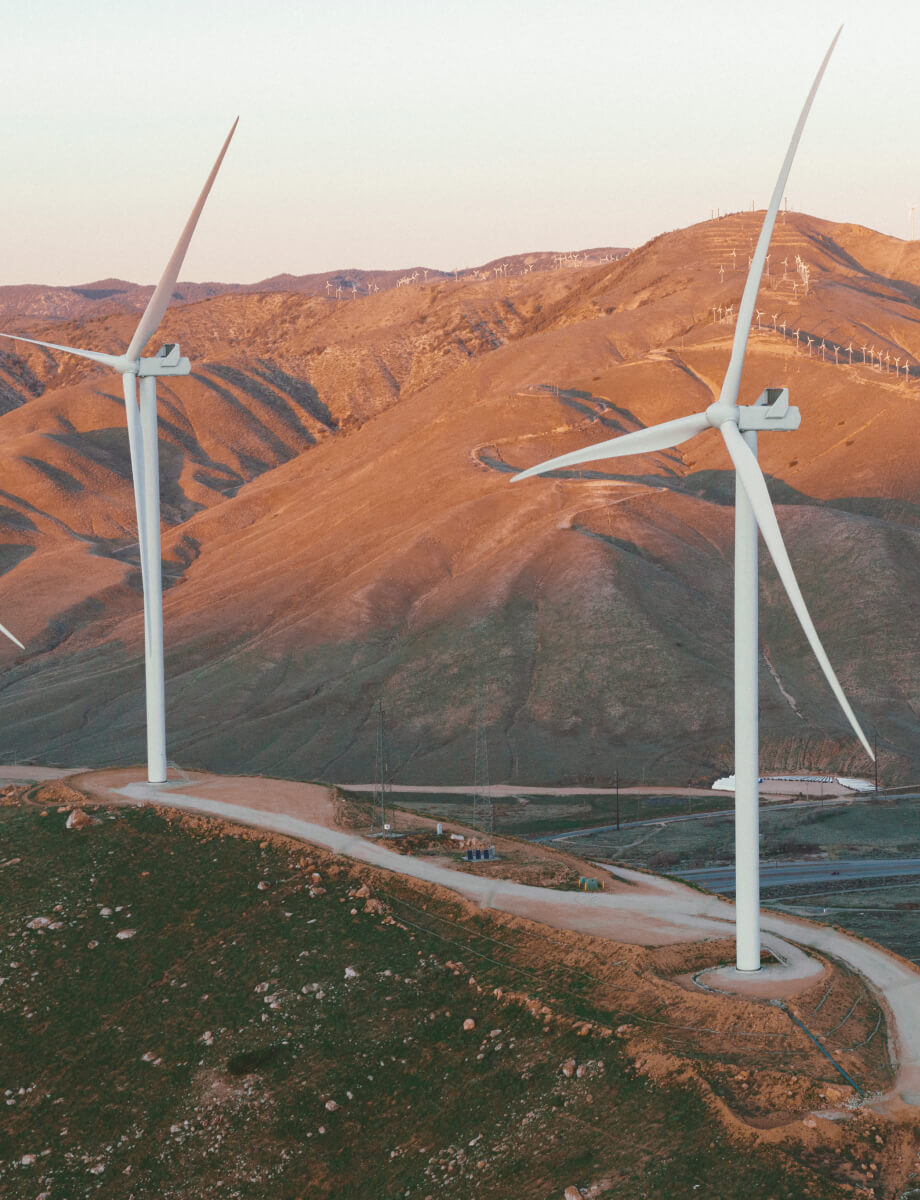 Wind turbines line the hills of mountains.