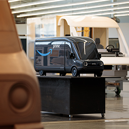 A miniature model of an Amazon electric delivery van is shown on top of a table. 