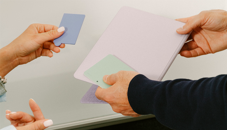 Two sets of hands holding design materials over a table.