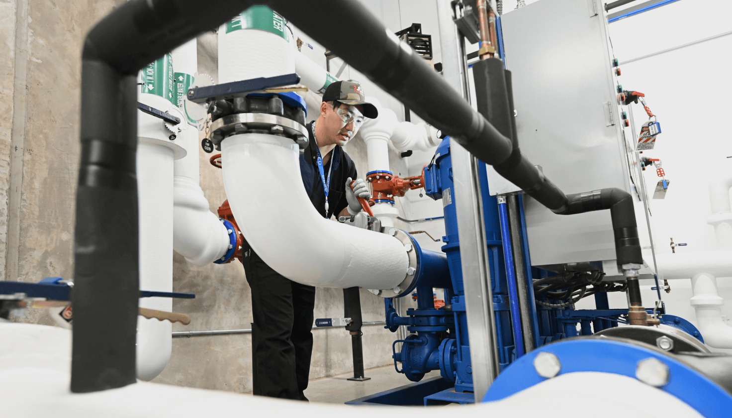 A person examines large pipes in a utility room. 